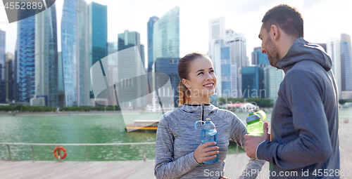 Image of couple with bottles of water over singapore city