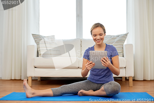 Image of woman with tablet computer doing yoga at home