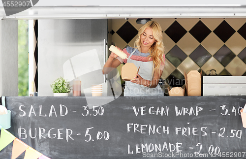 Image of happy saleswoman making wok at food truck