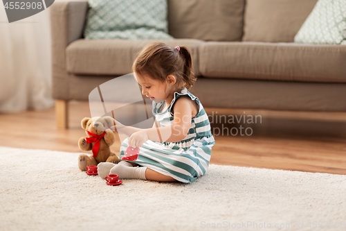 Image of little girl playing with toy tea set at home