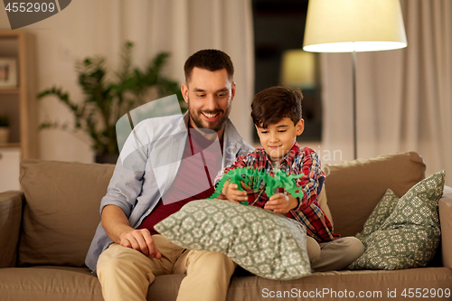 Image of father and son playing with toy dinosaur at home