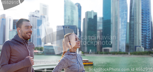 Image of happy couple with earphones running over singapore