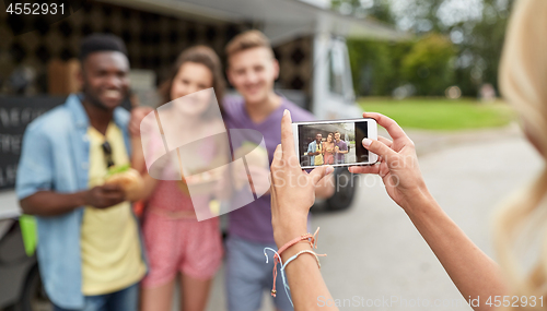 Image of woman photographing friends eating at food truck