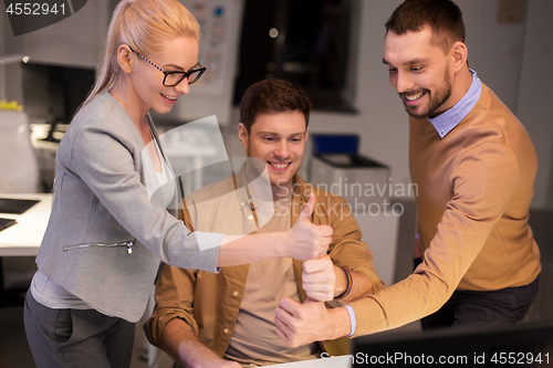 Image of business team making thumbs up gesture at office