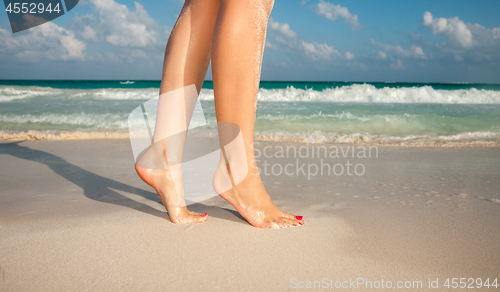 Image of closeup of woman legs walking on beach sand