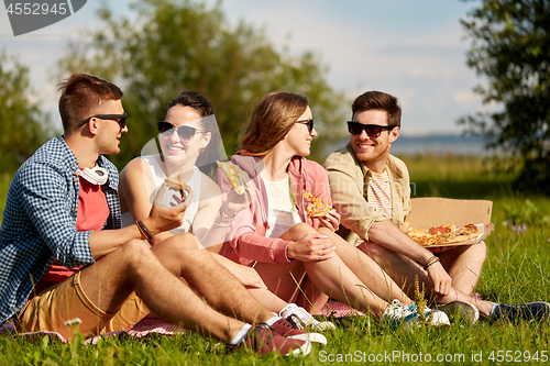 Image of friends eating pizza at picnic in summer park
