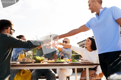 Image of happy friends toasting drinks at rooftop party