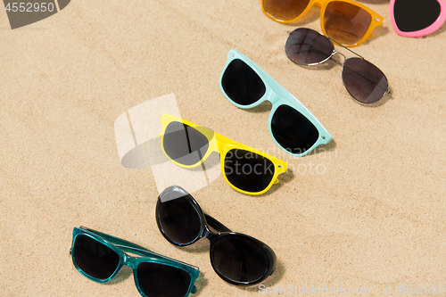 Image of different sunglasses on beach sand