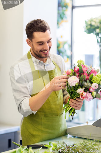 Image of smiling florist man making bunch at flower shop