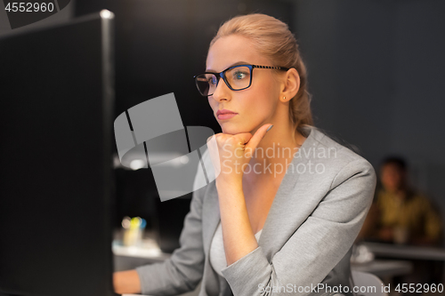 Image of businesswoman working at computer in night office