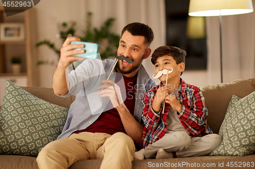 Image of father and son taking selfie at home