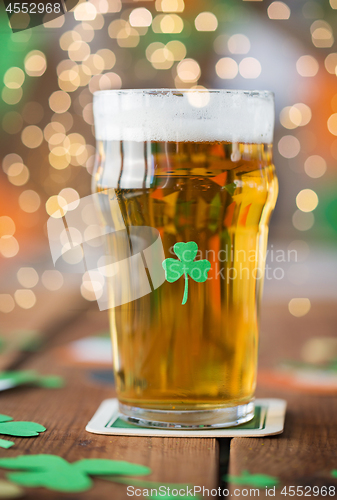 Image of close up of glass of beer with shamrock on table