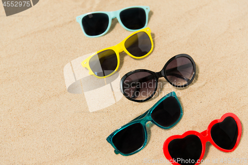 Image of different sunglasses on beach sand