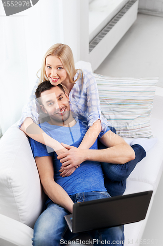 Image of happy couple with laptop computer at home