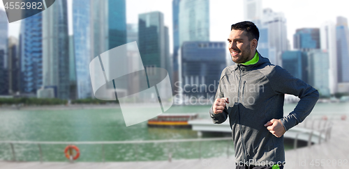 Image of happy young man running over singapore city