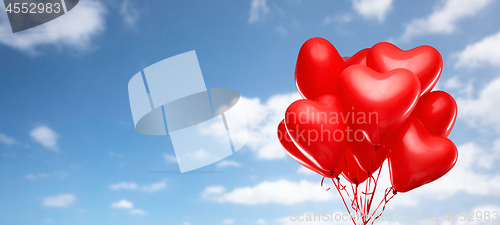 Image of red heart shaped helium balloons on white