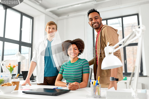 Image of happy creative team with laptop at office