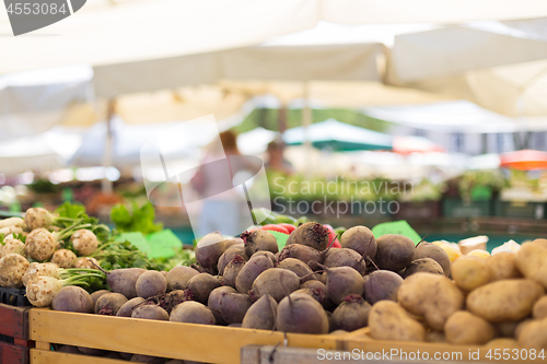 Image of Farmers\' food market stall with variety of organic vegetable. Vendor serving and chating with customers