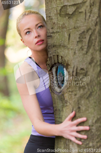 Image of Young woman hugging a tree.