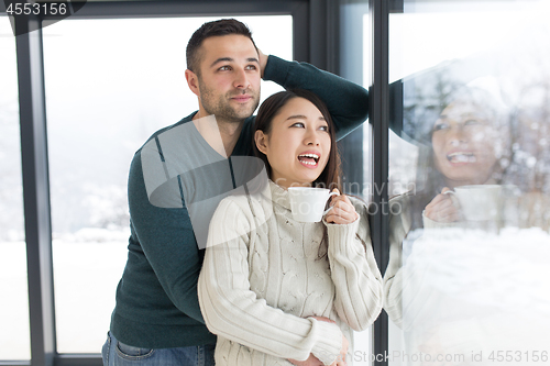 Image of multiethnic couple enjoying morning coffee by the window