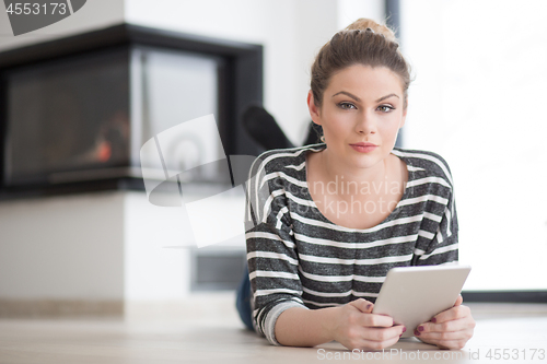 Image of woman using tablet computer in front of fireplace