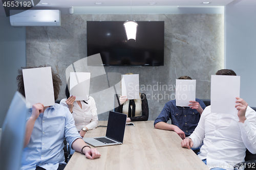 Image of startup business team holding a white paper over face