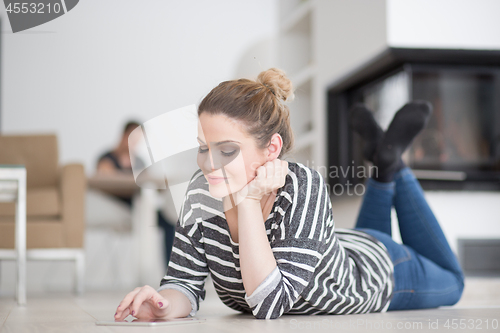 Image of woman using tablet computer in front of fireplace