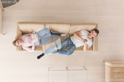 Image of Young couple on the sofa watching television top view