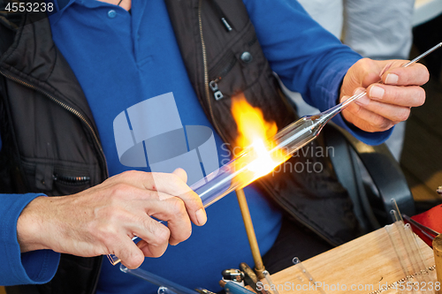 Image of Glass master hands heat up the glass rod.