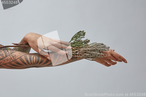 Image of A girl with a tattoo on her hands holding a flowers on a gray.