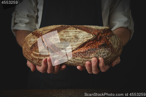 Image of Men\'s hands hold organic dark bread