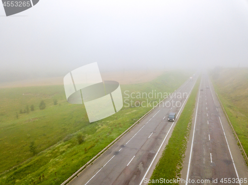 Image of Aerial view photo from the drone, landscape view of the fields and the road with cars in the fog