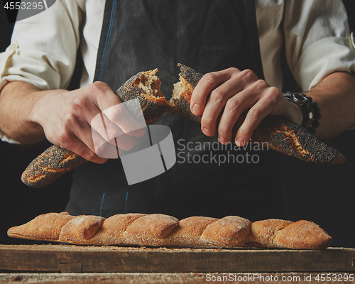 Image of baker man holding fresh halves of a baguette
