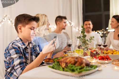 Image of boy with smartphone at family dinner party