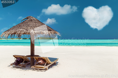 Image of two sunbeds under palapa on maldives beach