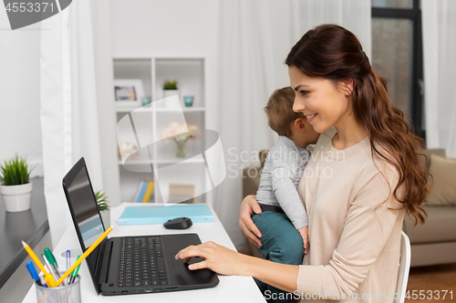 Image of happy mother with baby and laptop working at home