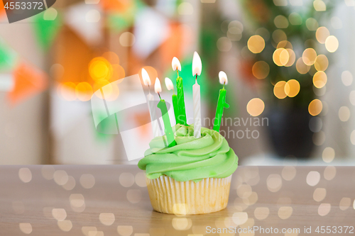 Image of green cupcake with six burning candles on table