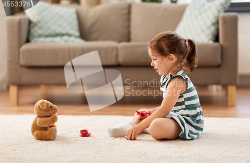 Image of little girl playing with toy tea set at home