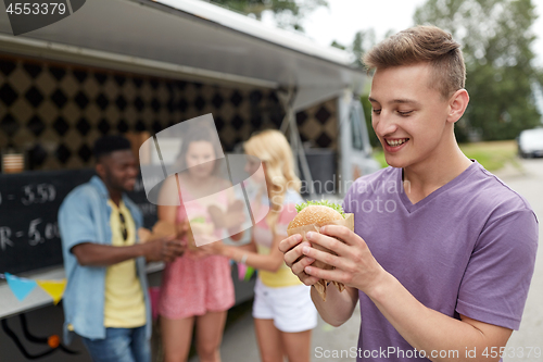 Image of happy man with hamburger and friends at food truck