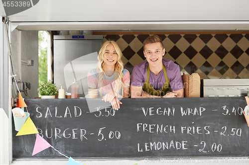 Image of couple of happy young sellers at food truck