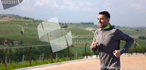 Image of happy young man running over country landscape