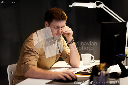 Image of tired businessman working late at night office