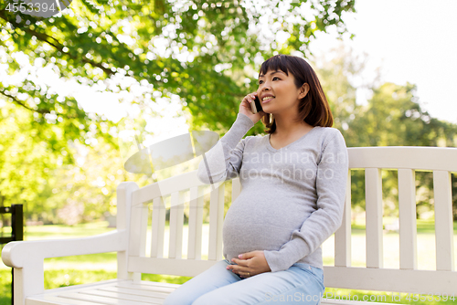 Image of pregnant asian woman calling on smartphone at park