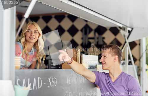 Image of saleswoman at food truck serving male customer