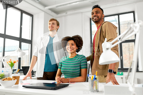 Image of happy creative team with laptop at office