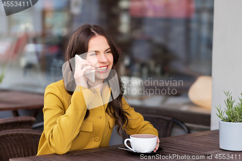 Image of teenage girl calling on smartphone at city cafe