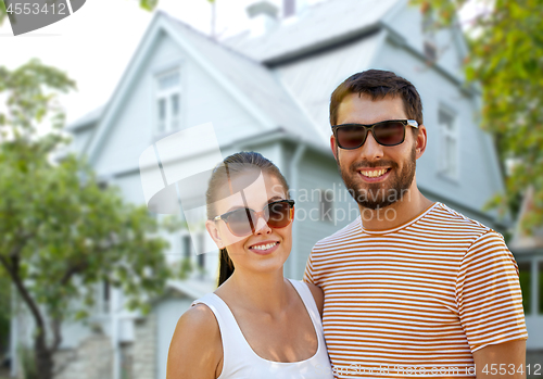 Image of happy couple in sunglasses in summer over house