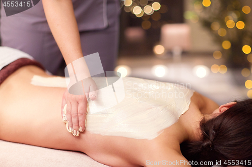 Image of woman having back massage with cream at spa