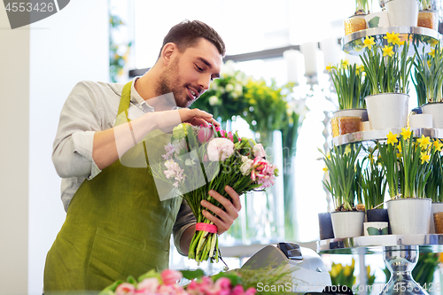 Image of smiling florist man making bunch at flower shop