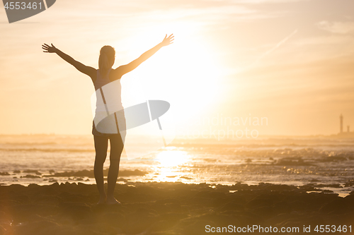 Image of Free woman enjoying freedom on beach at sunset.